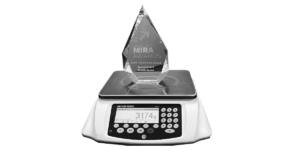 The image shows a glass Mira award placed on a scale.