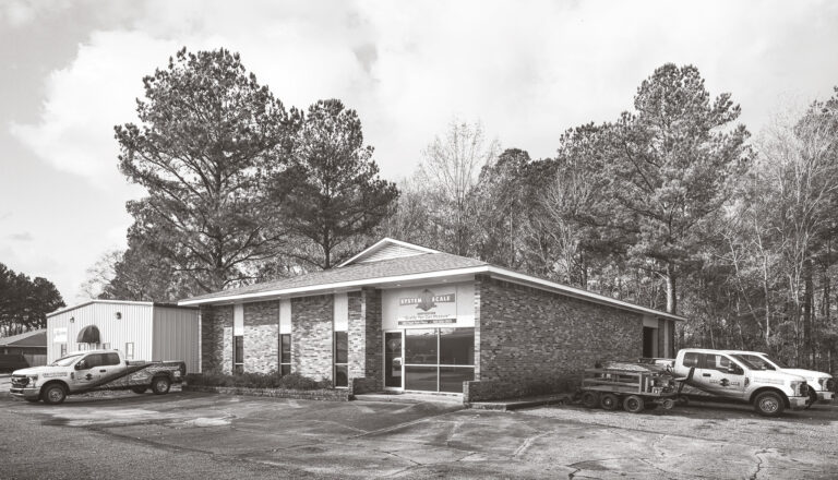 Exterior of System Scale office building with wrapped trucks parked outside.
