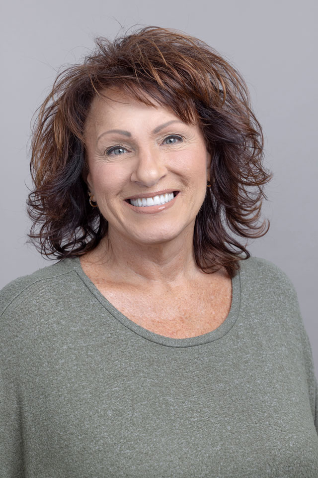 Headshot of woman with curly brown hair in green shirt