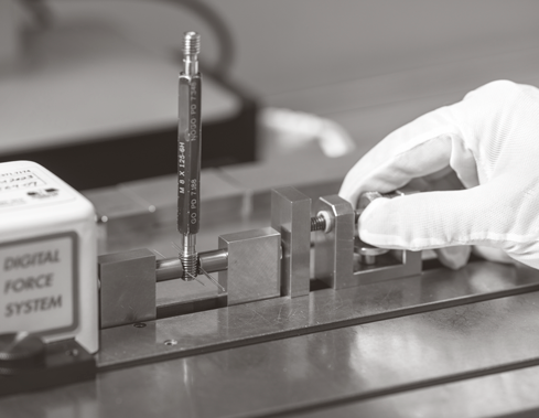 Gloved hands calibrating a threaded plug gauge
