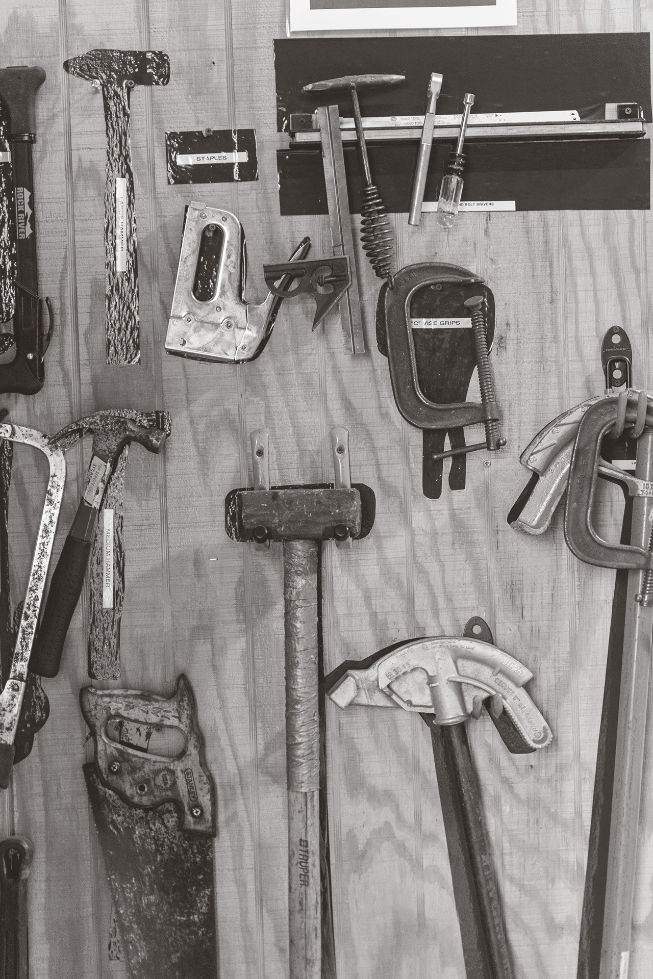 Mallet, saw, hammer, staple gun, and other tools hung on a wall
