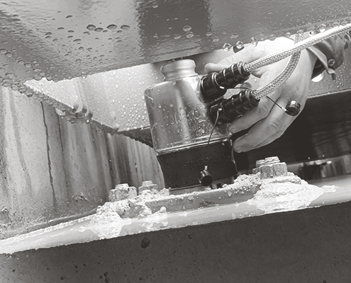 Tech hand installing a PDX PowerCell Loadcell under a truck scale.